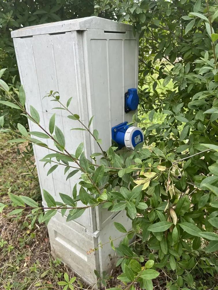 Skrzynka elektryczna do podłączenia kamperów ukryta wśród krzewów