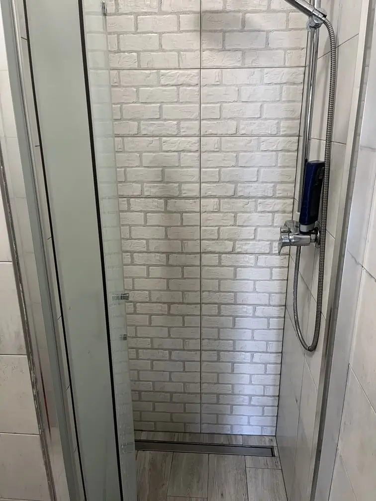 Kabina prysznicowa w hostelu Gadabout Camp z matowymi drzwiami.